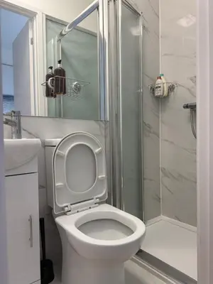 a bathroom with a white toilet and a shower at Private Rooms Near Acton Main Line Direct Elizabeth Line to Heathrow in Moffat