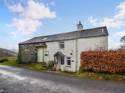 an old stone house on the side of a road at Derwent View in Applethwaite
