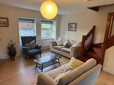 a living room with a couch and chairs and a table at Cozy cottage at the base of Sale and Ling Fell in Embleton