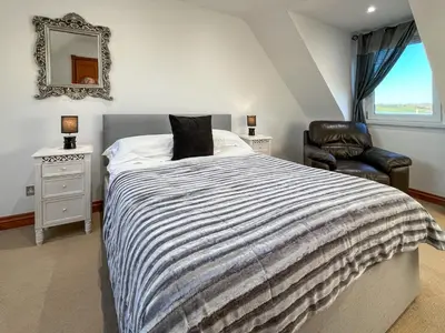 a bedroom with a bed and a chair and a mirror at Graeme-An-Taoiseach Uk50061 in Stranraer