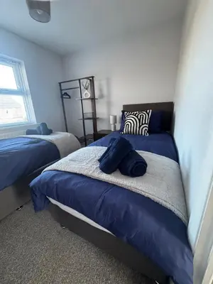 a bedroom with two beds with blue sheets and a window at Oakleigh Way, Carlisle - 2 Bedroom, sleeps 4, Fully furnished in Carlisle