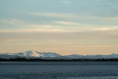 a view of snow capped mountains from the water at River View Cottages in Annan