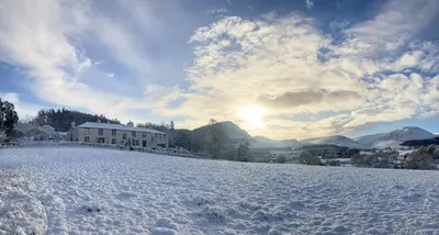 a snow covered field with a house in the background at Scale Hill Hotel in Loweswater