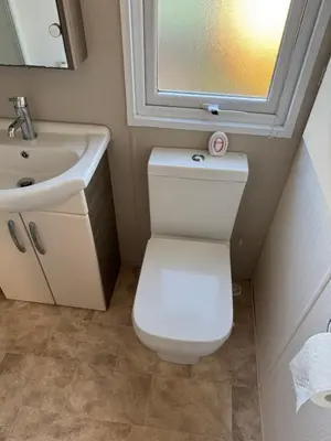 a bathroom with a toilet and a sink and a mirror at Turnberry Holiday Park Amazing Sea View in Girvan