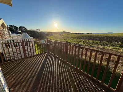 a wooden deck with a view of a field at Turnberry Holiday Park Amazing Sea View in Girvan