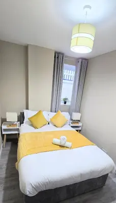 a bedroom with a large bed with a yellow blanket at One Old Creamery in Sandhead