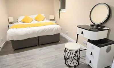 a bedroom with a bed with a mirror and a stool at One Old Creamery in Sandhead