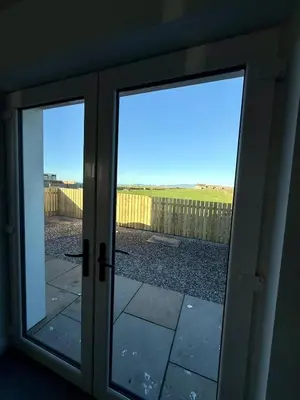 a sliding glass door with a view of a yard at Black Dub Cottage in Allonby