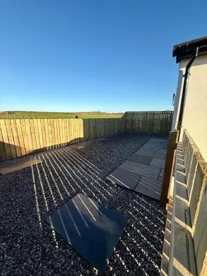 a building with a fence next to a sidewalk at Black Dub Cottage in Allonby