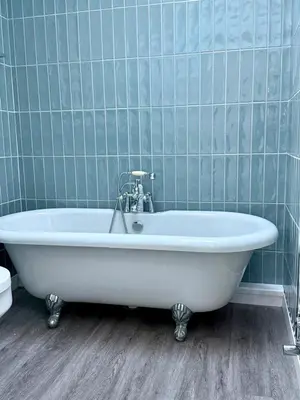 a white bath tub in a bathroom with blue tiles at Black Dub Cottage in Allonby