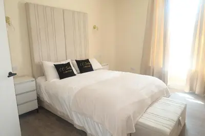 a white bedroom with a white bed and a window at Luxury one bedroom apartment in Dumfries