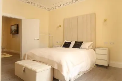 a white bedroom with a large bed and a white door at Luxury one bedroom apartment in Dumfries