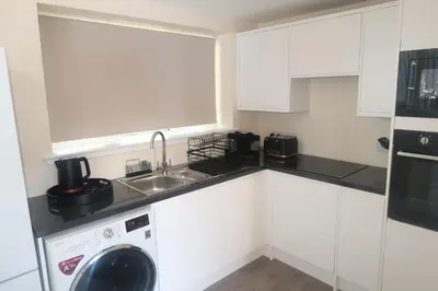 a white kitchen with a sink and a dishwasher at Luxury one bedroom apartment in Dumfries