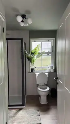 a bathroom with a toilet and a window and a plant at Cosy Cottage in Charming Village Close to Beach - Pass the Keys in Kirkbean