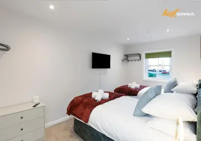 a bedroom with two beds and a tv on the wall at 2 Bed Flat in Airdrie I Sleeps 4 I Parking in Moffat