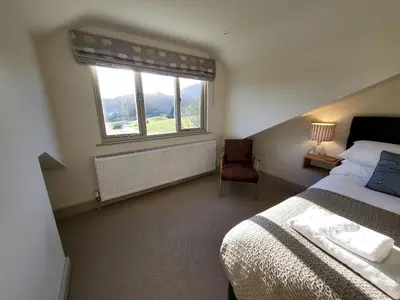 a bedroom with a bed and a window and a chair at Wetherlam View Little Langdale in Little Langdale