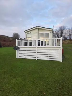 a house with a white fence in a field at Noah's Luxe Retreats in Newton Stewart
