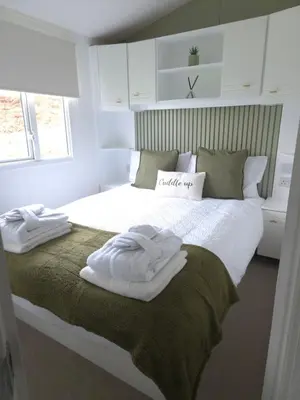 a bedroom with a bed with two towels on it at Noah's Luxe Retreats in Newton Stewart