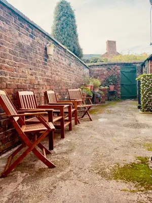 three wooden chairs sitting next to a brick wall at The old townhouse in Carlisle