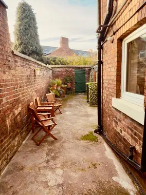 a patio with two wooden chairs and a window at The old townhouse in Carlisle