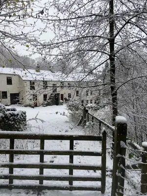 a snow covered yard with a fence and a house at 3 Millbeck Cottage in Keswick