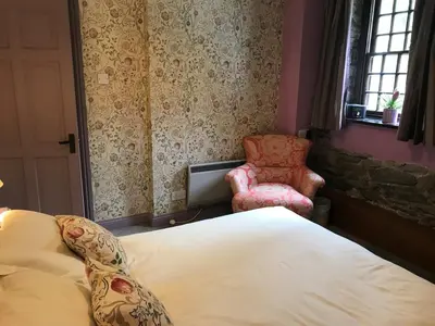 a bedroom with a bed and a chair and a window at 3 Millbeck Cottage in Keswick
