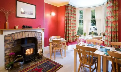 a living room with a fireplace and a table and chairs at Burnside B&B in Keswick