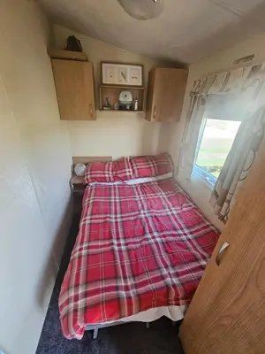 a bed with a plaid blanket in a small room at Number34 in Drummore