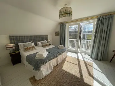 a bedroom with a bed and a large window at Keeper's Cottage at Slogarie Estate in Castle Douglas