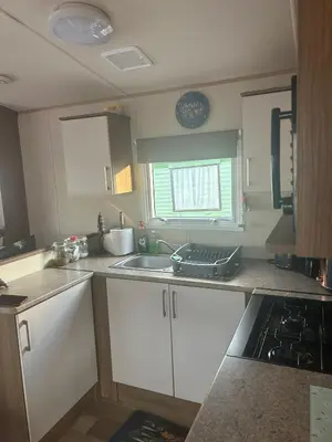a kitchen with white cabinets and a sink and a window at BZ Green Haven Caravan in Ballantrae