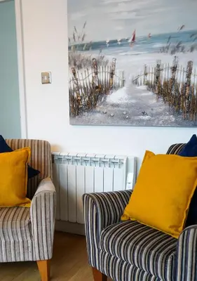 a living room with two chairs and a painting on the wall at Coppet Cove - 2 Bedroom Apartment - Saundersfoot in Moffat