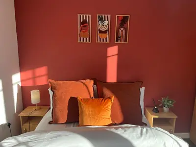 a bedroom with red walls and a bed with orange pillows at 3-Bedroom house near Manchester City Centre in Moffat
