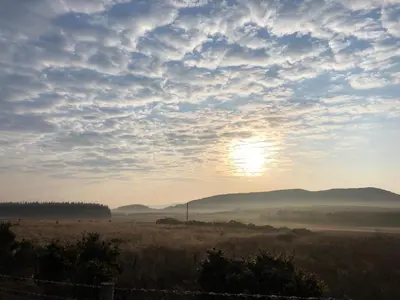 a sunset in a field with the sun in the sky at Barnharrow Holiday Park in Newton Stewart