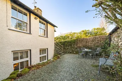a garden with a table and chairs in front of a house at Ben Place Cottage - Grasmere in Grasmere