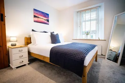 a bedroom with a bed and a dresser and a window at Cosy Cottage on edge of Lake District in Little Broughton