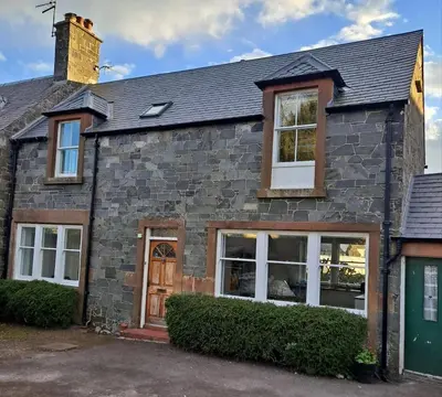 a brick house with a green door at Cosy Cottage in Moffat, South Scotland in Moffat