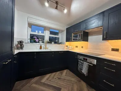 a kitchen with black cabinets and a sink at Riverview House in Minnigaff