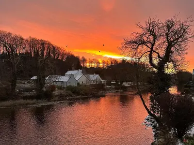a sunset over a river with trees and houses at Riverview House in Minnigaff