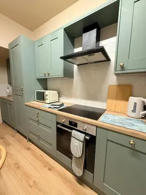 a kitchen with green cabinets and a stove top oven at Contractor 4BD Carlisle Long Stay w Wi-Fi, Washer, Smart TVs & Parking in Carlisle