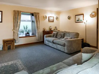 a living room with a couch and a window at East Challoch Farm Dairy Cottage in Stranraer