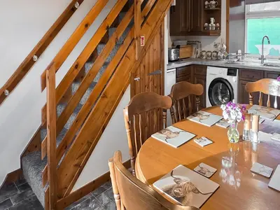 a dining room with a table and a kitchen at East Challoch Farm Dairy Cottage in Stranraer