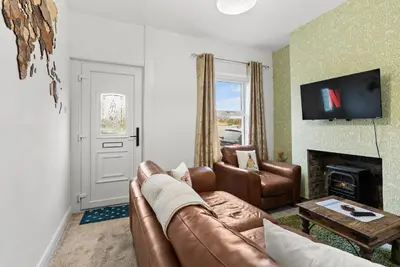 a living room with a leather couch and a fireplace at Vintage 2 Bed House in Lamplugh in Lamplugh