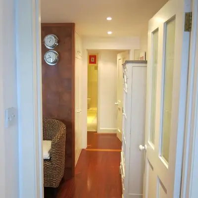 a hallway with a clock on the wall and a chair at THE WHEEL,Harbour view apartment for two - private front entrance and patio in Moffat