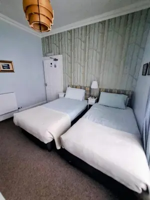 two beds in a room with white sheets at Brewery house in Newton Stewart