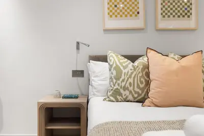 a living room with a couch with pillows and a table at Bright 3BR London Flat w Full Kitchen in Moffat