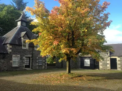 an autumn tree in front of an old building at Holiday Home Gehöft 4 by Interhome in Tweedsmuir