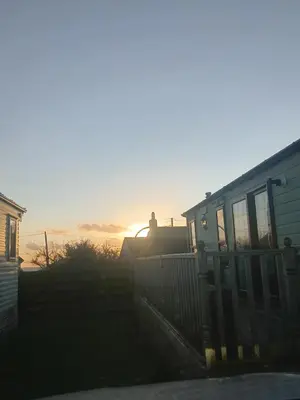 a house with the sunset in the background at 'Sunset Lodge' Peaceful Coastal Retreat with Hot Tub in Monreith