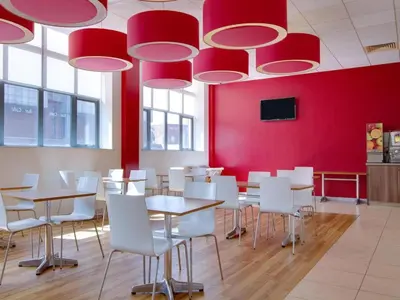 a dining room with red walls and tables and white chairs at Travelodge Carlisle Central in Carlisle
