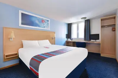 a hotel room with a large bed and a desk at Travelodge Carlisle Todhills in Rockcliffe