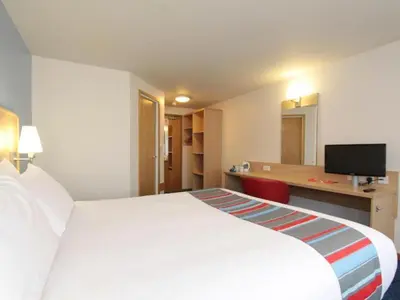 a hotel room with a large white bed and a desk at Travelodge Carlisle Todhills in Rockcliffe
